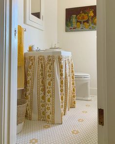 a white toilet sitting next to a bathroom sink under a painting on the wall above it