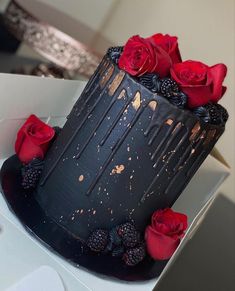 a chocolate cake with blackberries and red roses on the top is ready to be eaten