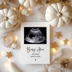 a baby announcement card surrounded by white pumpkins