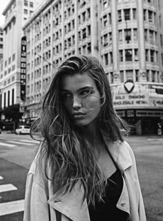 a woman with long hair standing on the street