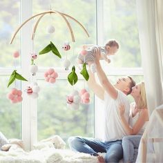 a man and woman holding a baby in front of a window