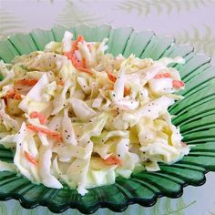 a green bowl filled with coleslaw on top of a table