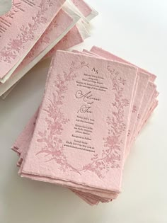 pink wedding cards with floral designs on the front and back are folded up in rows