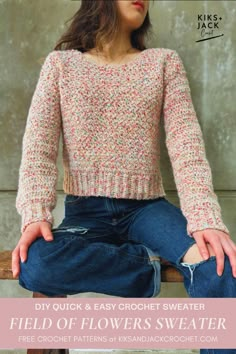 a woman sitting on top of a wooden bench wearing jeans and a knitted sweater