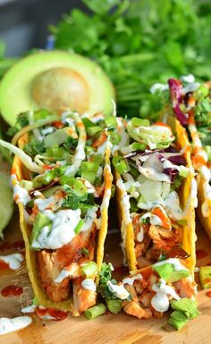 chicken tacos with avocado, cilantro and sour cream sauce on a cutting board