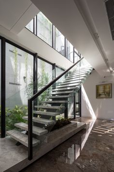 an indoor stair case with glass railings and plants on the side, along with concrete steps