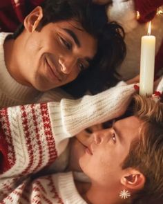 two people laying next to each other with a candle