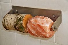 a piece of wood and some kind of rock hanging on a metal holder in a bathroom