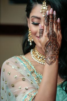 a woman with henna on her hand and jewelry around her neck, smiling at the camera