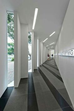 the hallway is lined with white columns and black and white striped flooring, along with two people walking down one side