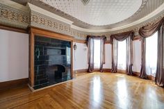 an empty room with wood flooring and large windows in the center is decorated with gold trim