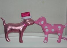 two pink and white dog figurines on top of a refrigerator