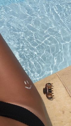 a close up of a person's legs next to a swimming pool with clear blue water