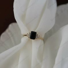 a black and white diamond ring sitting on top of a white flower covered in fabric