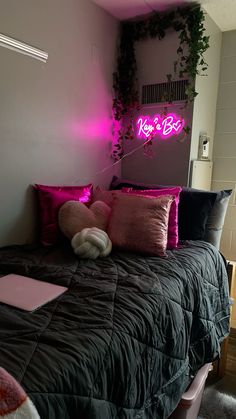 a bed that has some pillows on it and a neon sign in the corner behind it