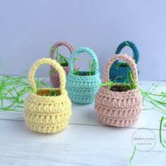 three crocheted baskets sitting on top of a white wooden table next to grass