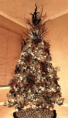 a decorated christmas tree in the corner of a room with shutters on the windowsill