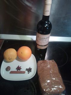 a bottle of wine sitting on top of a counter next to an orange and some spices