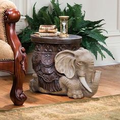 an elephant statue sitting on top of a table next to a chair and potted plant