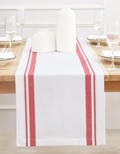 the table is set with white and red linens, wine glasses, and napkins