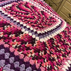 a crocheted blanket is laying on top of a bed with drawers and dressers in the background