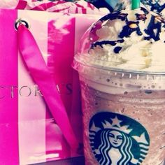 a starbucks drink with whipped cream and chocolate sprinkles on the top, next to a pink gift bag