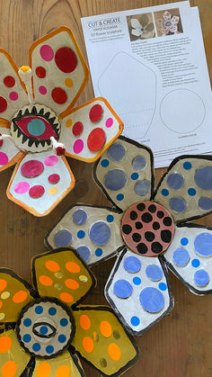 paper plates with painted flowers sitting on top of a wooden table next to a piece of paper