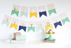 a birthday banner is hanging on the wall next to some books and presents, with confetti scattered around it