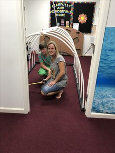 a woman kneeling down next to a child on the floor in front of an open door