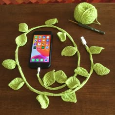 a cell phone is hooked up to a charger on a table with green leaves