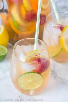 two glasses filled with lemonade, raspberries and limes