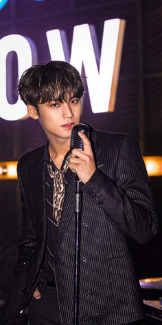 a young man holding a microphone in front of a sign with the word wow on it