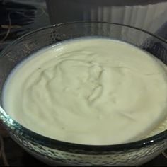 a glass bowl filled with cream sitting on top of a table