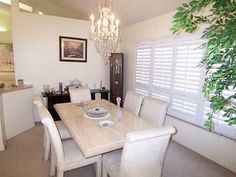 a dining room table with white chairs and a chandelier