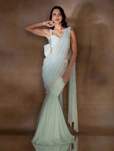 Mint georgette fishtail sari featuring an attached pre-draped pallu hand embellished with ivory pearls & glass beads & tassles. Paired with a stylised organza crop with embellished straps & an oversized bow at the back.From Shloka Khialani's Winter Sun collection.DELIVERY TIMEPlease allow 6-8 weeks for your outfit to arrive.FABRIC DETAILSGeorgette, Organza, CrepeProfessional cleaning only. Hand Embellished Georgette Pre-draped Saree, Wedding Hand Embellished Georgette Pre-draped Saree, Hand Embellished Georgette Pre-draped Saree For Wedding, Designer Draped Hand Embellished Saree, Party Wear Pre-draped Saree With Pearl Embroidery For Reception, Designer Pre-draped Saree With Pearl Embroidery, Hand Embellished Georgette Pre-draped Saree For Reception, Hand Embellished Georgette Saree With Draped Design, Designer Hand Embellished Draped Saree