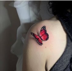 a woman's shoulder with a red butterfly tattoo on the left side of her arm