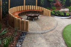 a wooden bench sitting on top of a gravel covered ground next to a fire pit