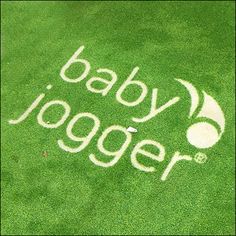 an image of a logo on the grass with white writing that says baby jogger