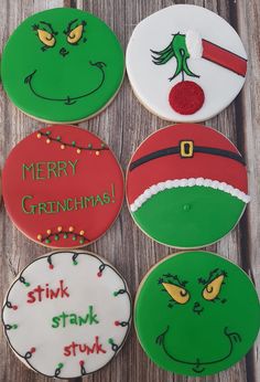 four decorated cookies on top of a wooden table with words merry grinchmas, stink stink and santa clause