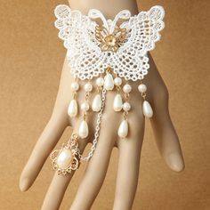 a mannequin's hand is adorned with white lace, pearls and gold jewelry