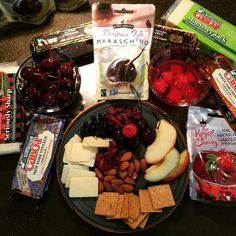 an assortment of fruit, crackers, and nuts on a plate next to some snacks