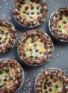 six chocolate cupcakes with sprinkles in them on a gray surface