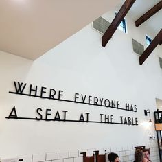 two people sitting at a table in front of a sign that says where everyone has a seat at the table