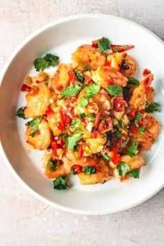 a white plate topped with shrimp and veggies on top of a marble table