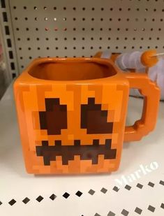 an orange mug with a face on it is sitting on a shelf in a store