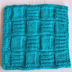 a blue crocheted dishcloth on a white surface with one square in the middle