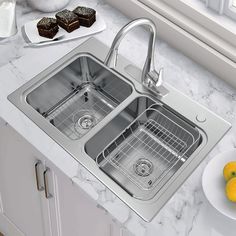 a double sink in a kitchen with marble counter tops and white cabinets next to a bowl of lemons