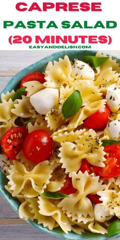 a blue bowl filled with pasta salad and topped with tomatoes, mozzarella cheese and basil