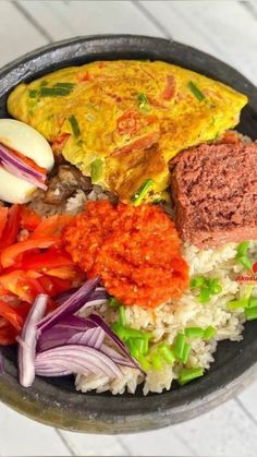 a black bowl filled with rice, meat and veggies next to an egg