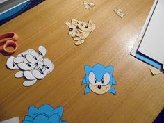 some stickers on a wooden table with scissors and other things around them that are cut out to look like sonic the hedgehogs